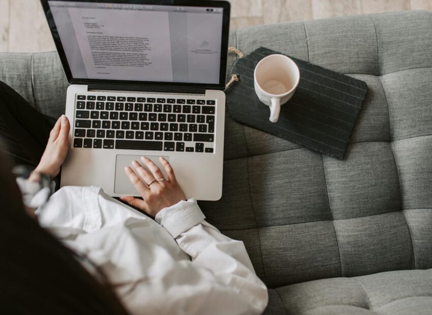 crop woman using laptop on sofa at home